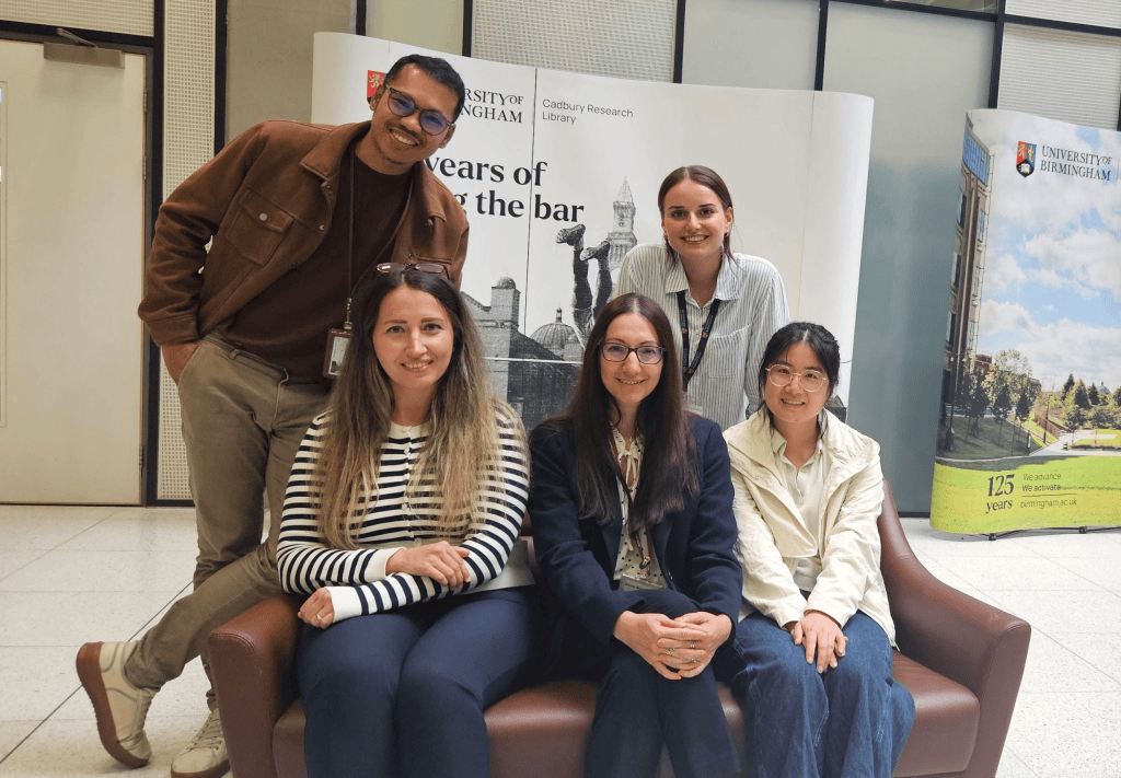 Zania Stamataki's team welcomes Dr Cosar, scientists are posing for a photo around a sofa at the library.